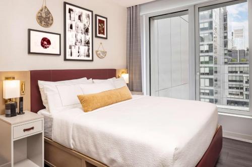 a bedroom with a large bed and a large window at Hilton Club The Central at 5th New York in New York
