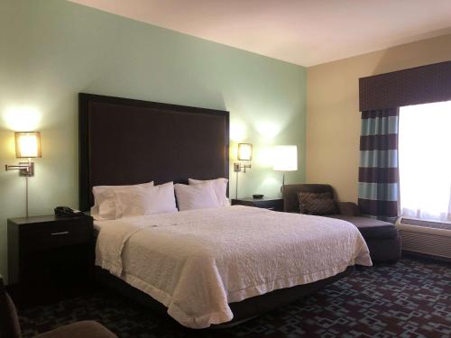 a hotel room with a large bed and a chair at Hampton Inn & Suites Nashville at Opryland in Nashville