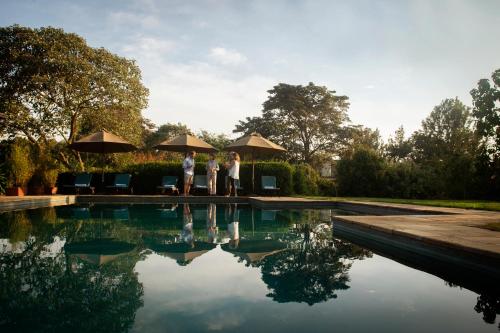 two people standing next to a pool with umbrellas at Katambuga House in Arusha