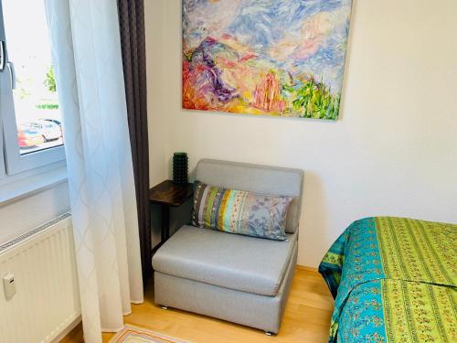 1 dormitorio con silla y una pintura en la pared en AnNa Home & Sunny Home Apartments en Karlsruhe