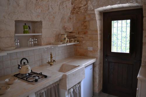 une cuisine avec un évier, une fenêtre et une porte dans l'établissement Il Gelso Selvatico, à Locorotondo