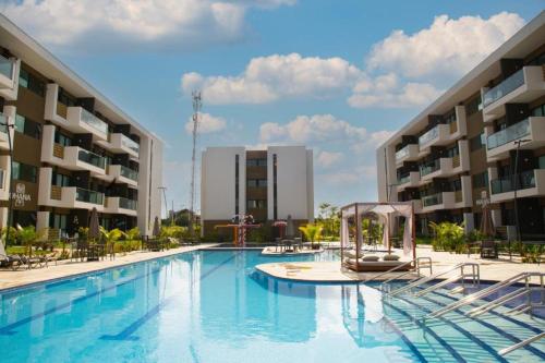 uma grande piscina em frente a dois edifícios em Mana Beach Muro Alto Resort em Porto de Galinhas