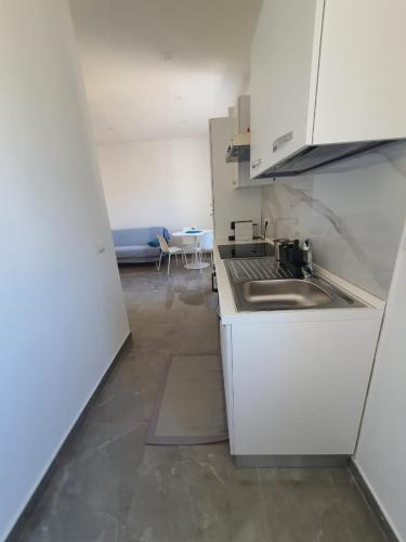 cocina con armarios blancos, fregadero y mesa en Deviveschi guest house, en Castellammare di Stabia