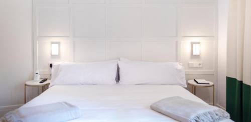a bed with white sheets and pillows in a room at Room Mate Cosmo - City Centre, Valencia in Valencia