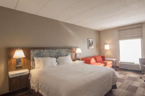 une chambre d'hôtel avec un lit et une chaise dans l'établissement Hampton Inn Medina, à Medina