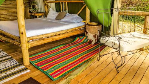 a porch with a bed and a colorful rug at Living Waters Resort in Jinja