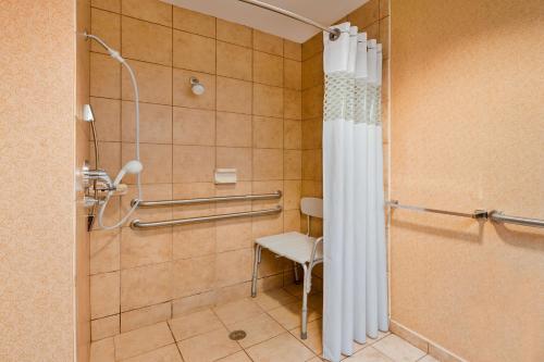 a bathroom with a shower with a toilet and a chair at Hampton Inn Marion in Marion