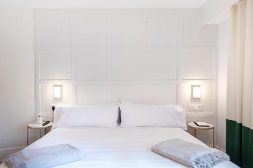 a white bed with white sheets and pillows on it at Room Mate Cosmo - City Centre, Valencia in Valencia
