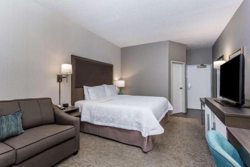 a hotel room with a bed and a couch at Hampton Inn Milwaukee Airport in Milwaukee