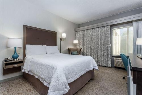 um quarto de hotel com uma cama grande e uma janela em Hampton Inn Milwaukee Airport em Milwaukee
