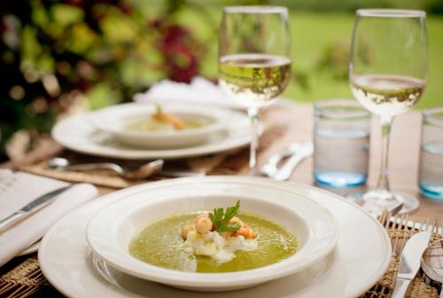 a table with a plate of soup and glasses of wine at Katambuga House in Arusha