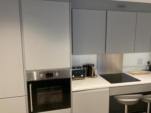 a kitchen with white cabinets and a stove top oven at Unique comfortable Apartment in Abbey Wood