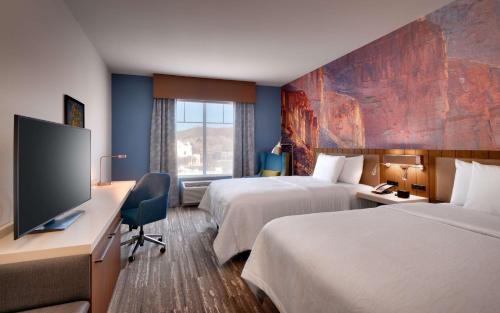 Habitación de hotel con 2 camas y escritorio con TV. en Hilton Garden Inn Prescott Downtown, Az, en Prescott