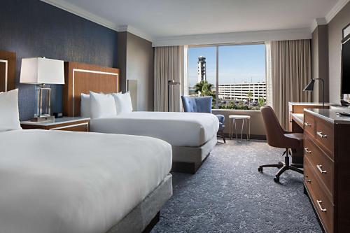 um quarto de hotel com duas camas e uma secretária em Hilton New Orleans Airport em Kenner