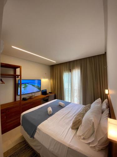 a bedroom with a large bed and a flat screen tv at Reserva BG - Vila Caju - Vista Mar - Barra Grande in Barra Grande