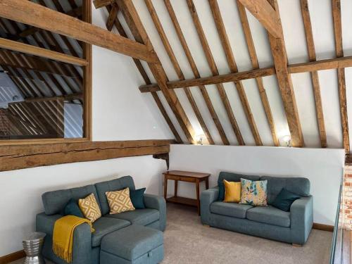 two couches in a living room with wooden ceilings at Grange Farm Barn, Filby in Filby