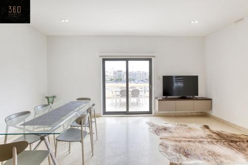 a white room with a dining table and a tv at Marina VIEW APT SLPs 9 with private terrace & BBQ by 360 Estates in Taʼ Xbiex
