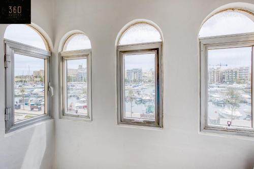 three windows in a white room with a view of a city at Marina VIEW APT SLPs 9 with private terrace & BBQ by 360 Estates in Taʼ Xbiex