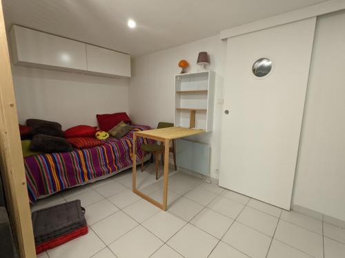 ein kleines Schlafzimmer mit einem Bett und einem Tisch in der Unterkunft Studio indépendant, accès piscine in Le Castellet