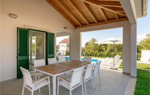a patio with a wooden table and white chairs at Villa Makarac in Milna