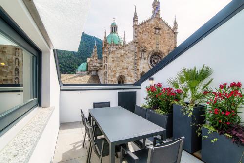 einen Balkon mit einem Tisch, Blumen und einer Kirche in der Unterkunft Dome's Magic - The House Of Travelers in Como