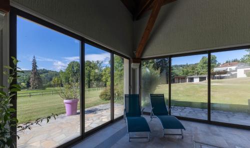 a screened in porch with blue chairs and large windows at Ma Tranquillite in Courpière