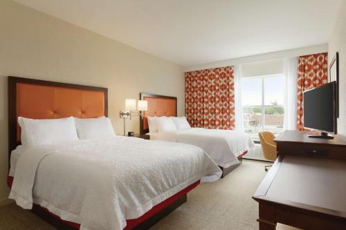 a hotel room with two beds and a television at Hampton Inn, St. Albans Vt in Saint Albans