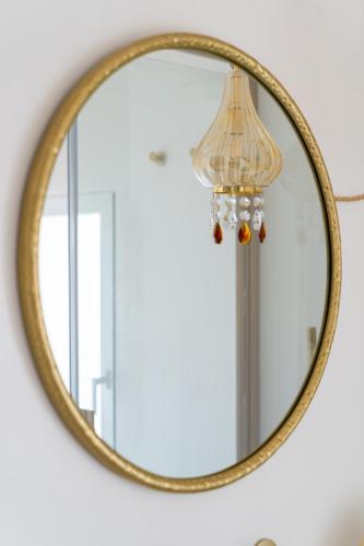 a gold mirror with a lamp on a wall at Dimore di Brando Vico Gelso in Polignano a Mare
