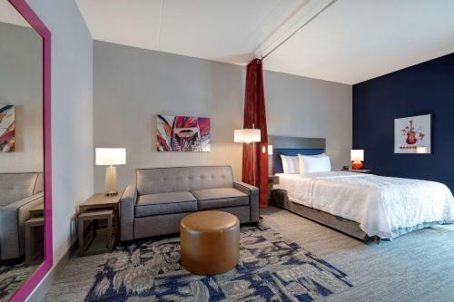 Home2 Suites By Hilton Nashville Downtown-Metrocenter في ناشفيل: غرفه فندقيه بسرير واريكه