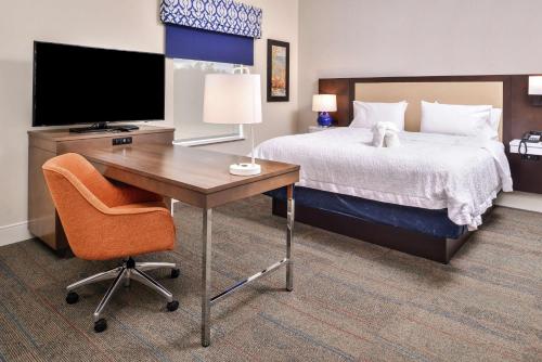 a bedroom with a bed and a desk with a television at Hampton Inn Benson in Benson