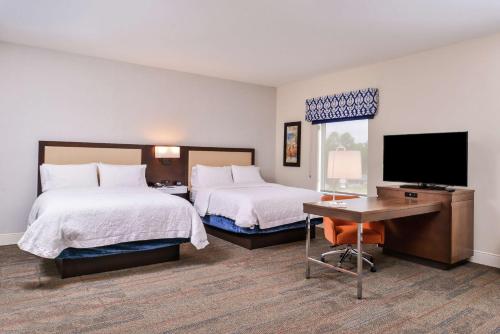 a hotel room with two beds and a desk and a television at Hampton Inn Benson in Benson