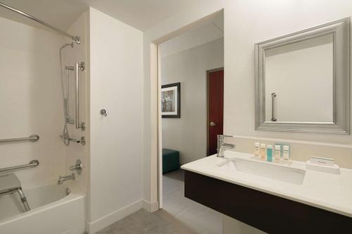 a bathroom with a sink and a mirror and a tub at Hampton Inn Reading/Wyomissing in Wyomissing