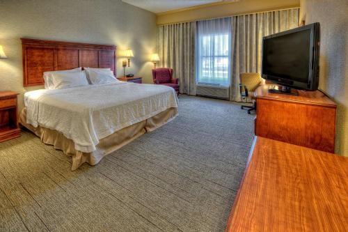 a hotel room with a bed and a flat screen tv at Hampton Inn Manning in Manning