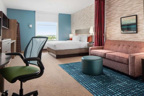 Home2 Suites By Hilton Rowlett Rockwall Marina في Rowlett: غرفه فندقيه بسرير واريكه