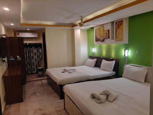 two beds in a room with green walls at Hotel Platinum in Kolkata