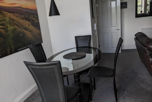 a dining room with a glass table and chairs at Immaculate 1-Bed Apartment in Merthyr Tydfil in Merthyr Tydfil