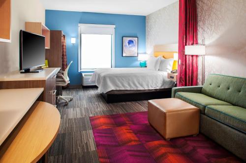 Home2 Suites By Hilton Lake Charles في ليك تشارلز: غرفه فندقيه بسرير واريكه