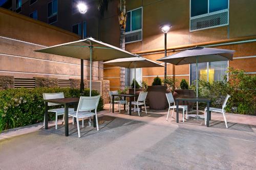 a group of tables and chairs with umbrellas at Hilton Garden Inn San Bernardino in San Bernardino