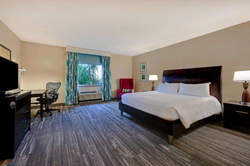 a hotel room with a bed and a desk and chair at Hilton Garden Inn San Bernardino in San Bernardino