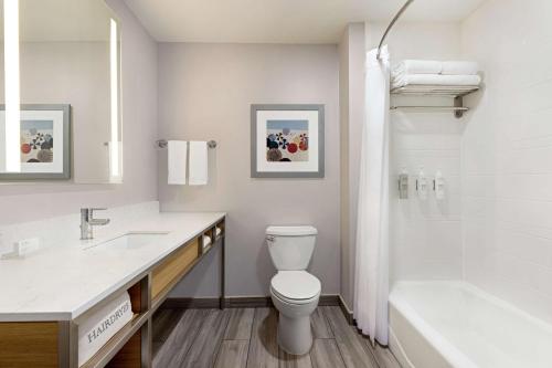 a bathroom with a toilet and a sink and a tub at Hilton Garden Inn South Padre Island in South Padre Island