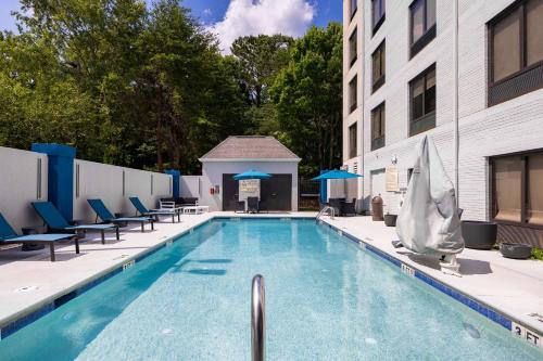 a swimming pool with chairs and a building at Hampton Inn & Suites Alpharetta Roswell in Alpharetta