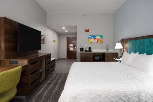 a hotel room with a bed and a flat screen tv at Hampton Inn & Suites Alpharetta Roswell in Alpharetta