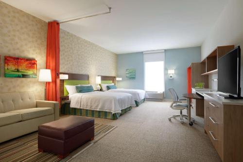 ダーラムにあるHome2 Suites by Hilton Durham Chapel Hillのベッドとソファ付きの広いホテルルームです。
