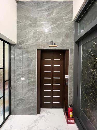 a bathroom with a brown door and a wall at Hualien Leo and Alley Elevator B&B in Hualien City