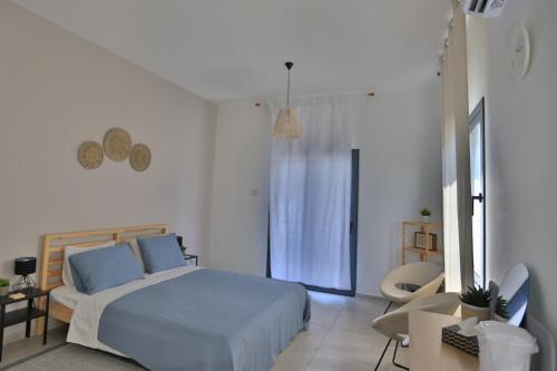 a white bedroom with a bed and a chair at Stunning Seaview Haven 3 min to Beach in Lapta in Kyrenia