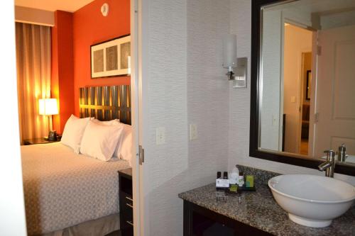 a bathroom with a bed and a sink and a mirror at Embassy Suites Palmdale in Palmdale