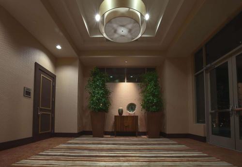 a hallway with two plants and a chandelier at Embassy Suites Palmdale in Palmdale
