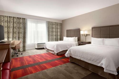 a hotel room with two beds and a desk at Hampton Inn By Hilton North Olmsted Cleveland Airport in North Olmsted