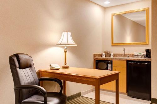 a hotel room with a desk with a lamp and a chair at Hampton Inn & Suites Addison in Addison