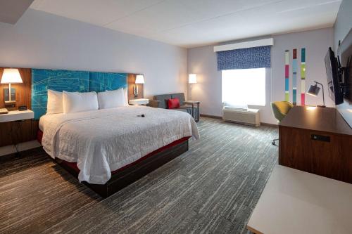 um quarto de hotel com uma cama grande e uma televisão em Hampton Inn & Suites Charlotte-Airport em Charlotte